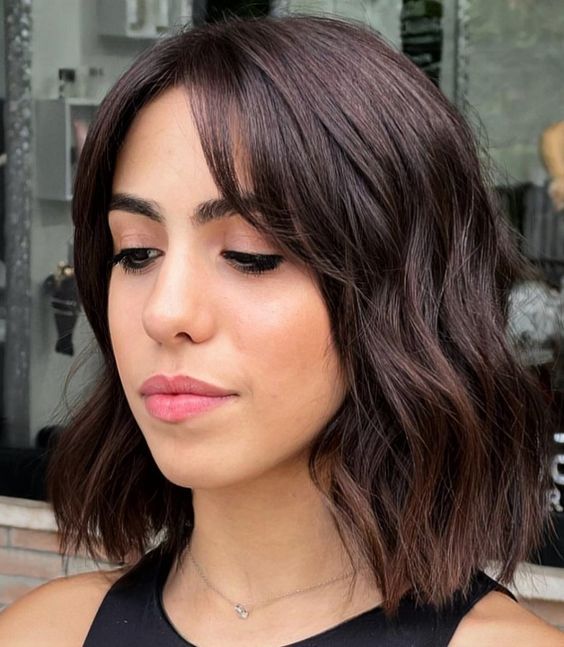 A dark brunette long bob with curtain bangs and waves is a chic and stylish idea to try