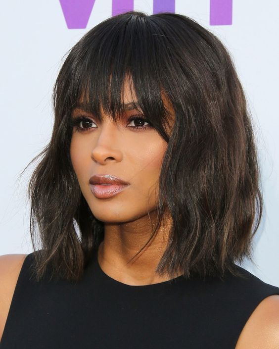 A stylish black and brown messy wave bob with overgrown bangs that add a messy and effortlessly chic touch