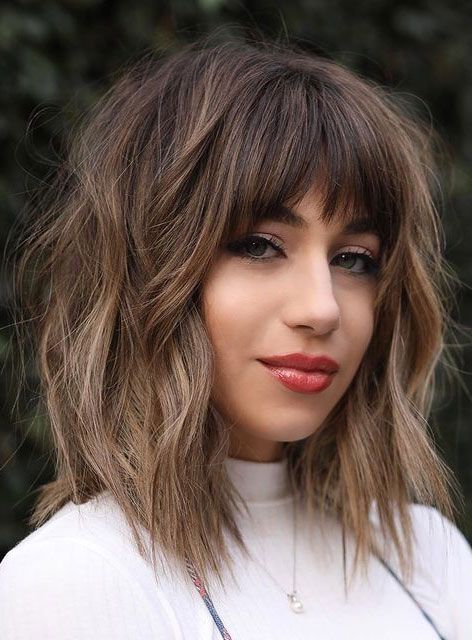 A super textural layered long bob haircut with Birkin bangs and bangs framing the face, with a slight ombre effect