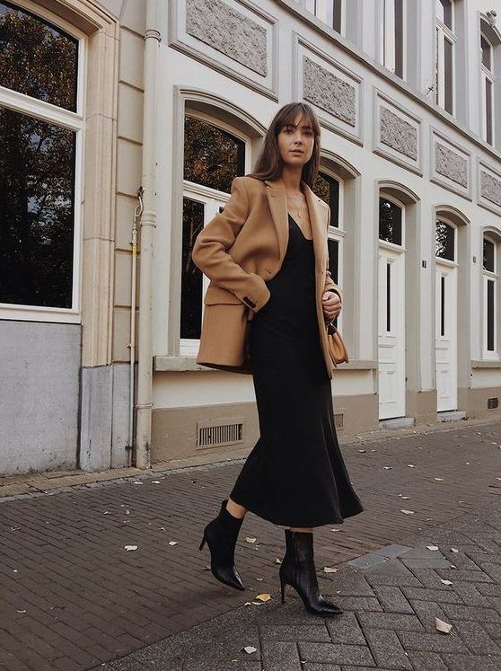 Black slip midi dress, black booties, and a camel blazer coat come together for an ultimately elegant look