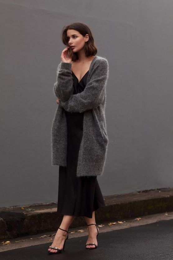 Black slip midi dress, black heels, and a grey oversized cardigan create a comfy and very feminine fall outfit