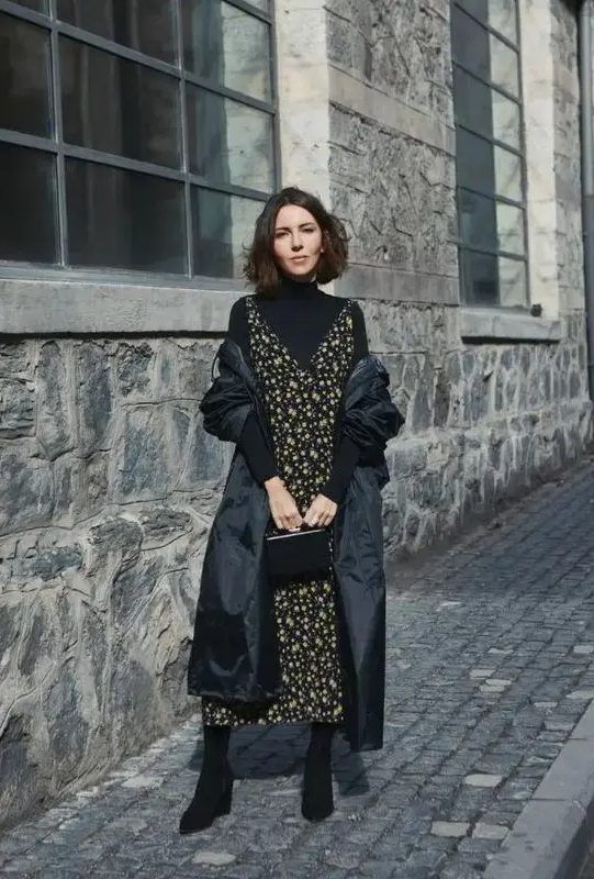 Black turtleneck under a moody floral midi dress, paired with sock boots, a small bag, and a puff midi coat