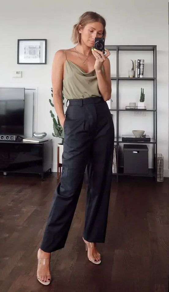 Bold wedding guest look with an olive green spaghetti strap top, black leather pants, clear heeled mules, and layered necklaces