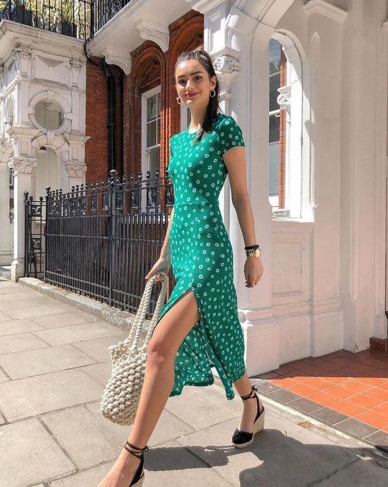 Bright green fitting midi dress with a high neckline, short sleeves, a side slit, espadrilles, and a woven bag