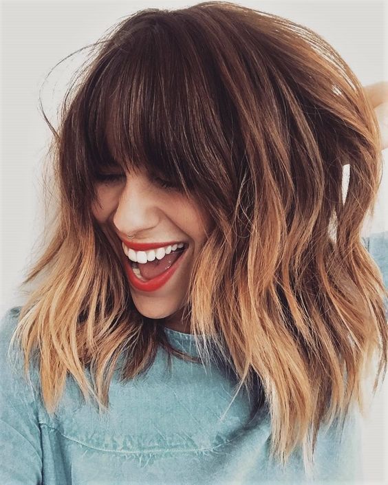 Brown layered long bob with copper highlights and classic, face-framing bangs, super chic and bold