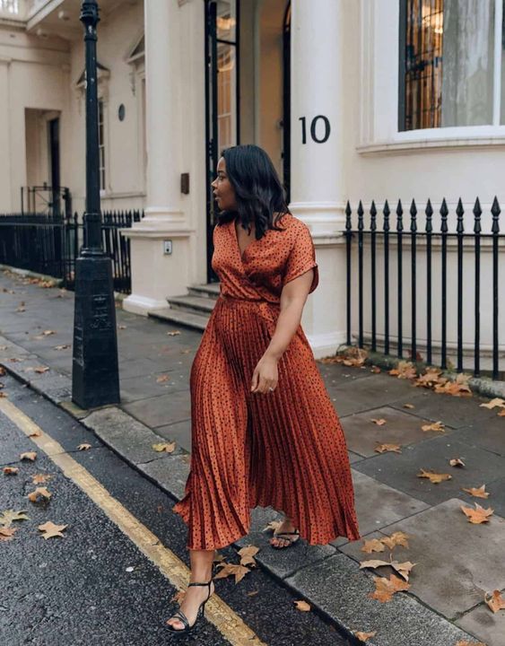 Burnt orange midi polka dot dress with a pleated skirt and black strappy shoes, a lovely fall wedding guest look