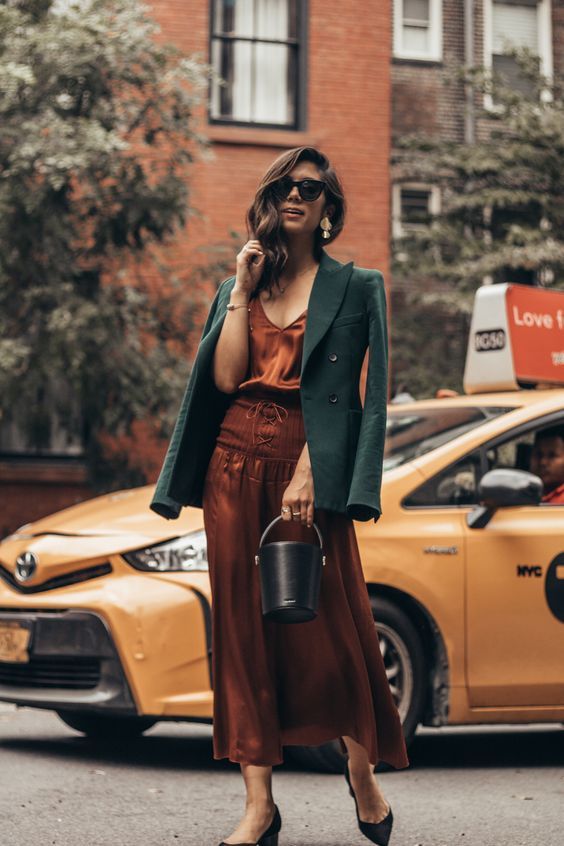 Burnt orange midi slip dress with lacing up, black shoes, green blazer, and black bucket bag, a cool combo