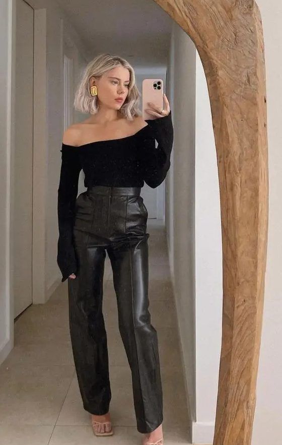 Classy guest outfit with a black off-the-shoulder top, black leather pants, strappy shoes, and statement earrings