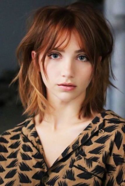 Copper shoulder-length layered and messy bob with brighter highlights and usual, overgrown bangs, bold
