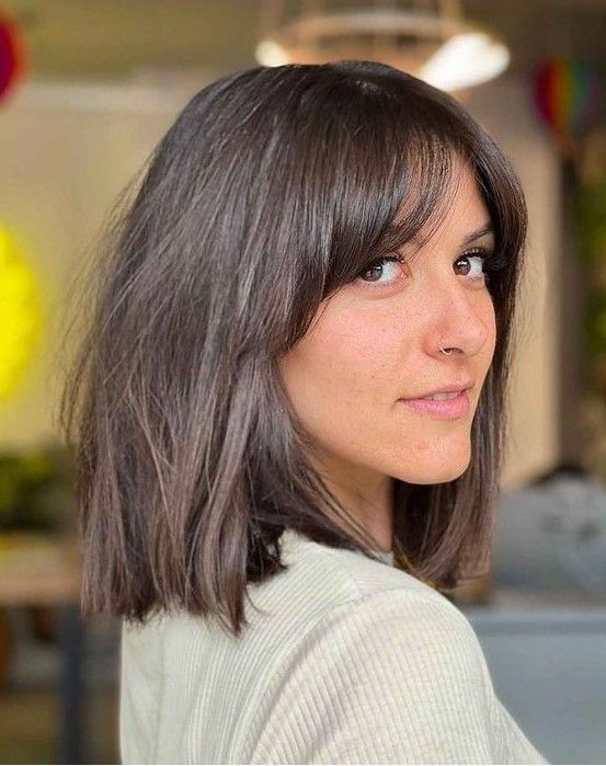 Dark brunette long bob with bottleneck bangs paired with curtain ones, a very chic and catchy idea