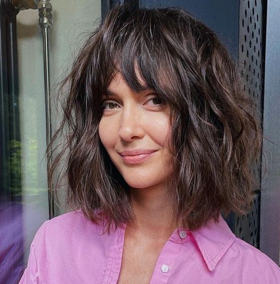Dark brunette shaggy long bob with a messy and thick fringe and a lot of messy waves, a lovely idea