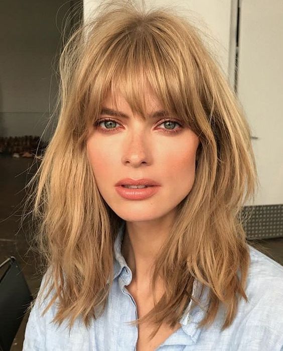 Layered honey blonde long bob with shaggy locks and overgrown, very natural bangs, inspired by the '70s
