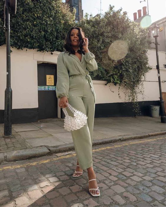 Light green jumpsuit, white strappy shoes, bead bag, an effortless spring wedding guest look