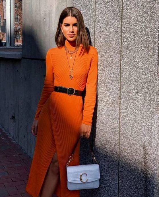 Lovely textural orange sweater dress with a black belt, layered necklaces, and a white monogrammed bag
