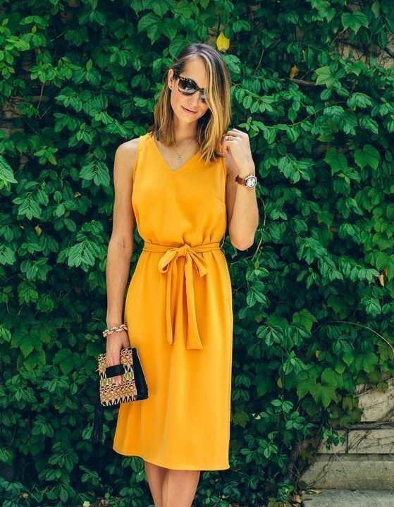 Marigold knee plain dress with thick straps, a sash, a whimsy printed bag, and a watch for a casual summer wedding