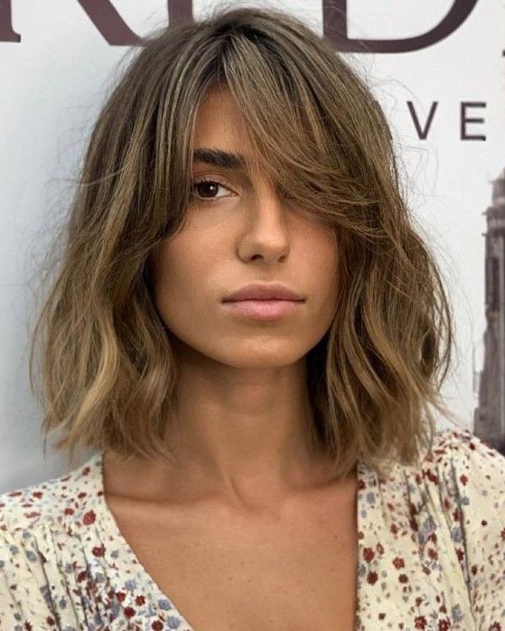 Messy bronde long bob with a darker root and waves plus curtain bangs to soften the look even more
