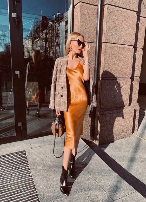 Orange slip midi dress, black boots, plaid blazer, and a brown bag for a refined fall outfit