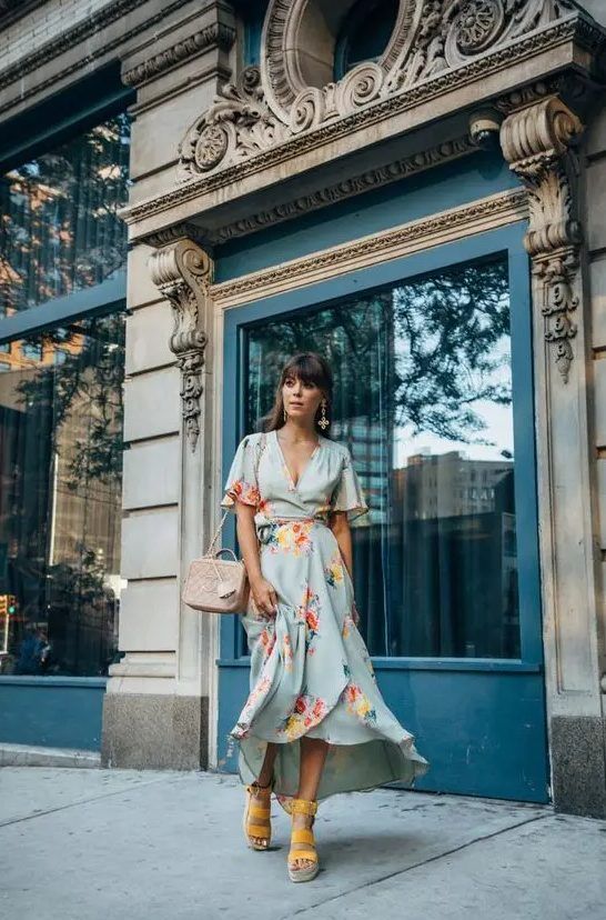 Pale blue floral wrap midi dress, blush bag, yellow platform shoes, and statement earrings, a perfect summer wedding ensemble
