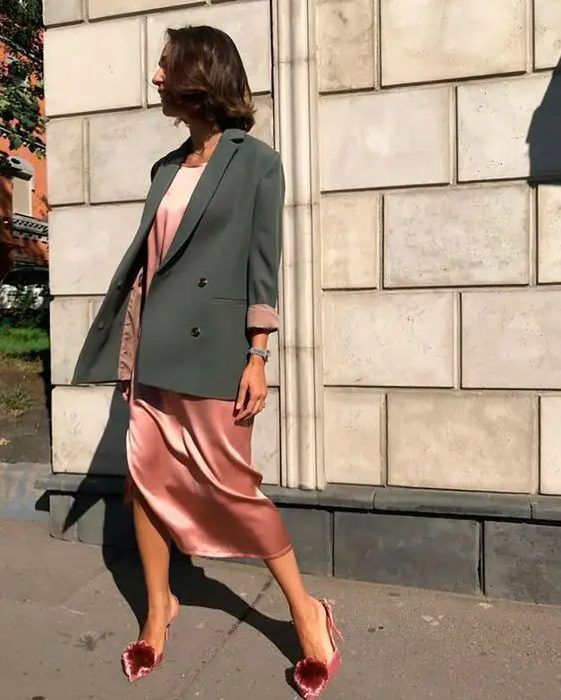 Pink slip midi dress, pink heels with pompoms, and a grey oversized blazer, a lovely and simple wedding guest look