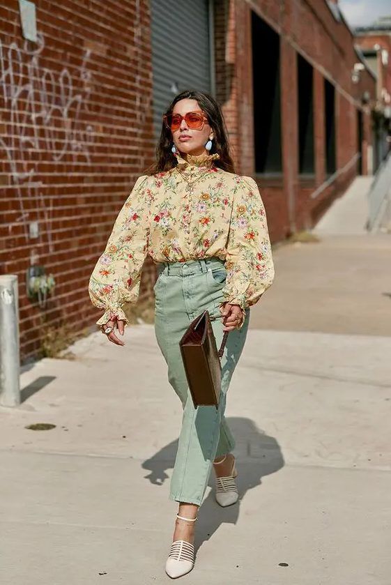 Pretty and elegant vintage-inspired wedding guest look with a tan floral blouse with puff sleeves, mint-colored pants, white shoes, and a brown bag