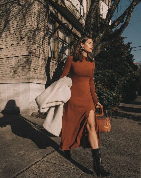 Rust midi A-line knit dress with long sleeves, a slit, a turtleneck, black cowboy boots, and a white faux fur coat