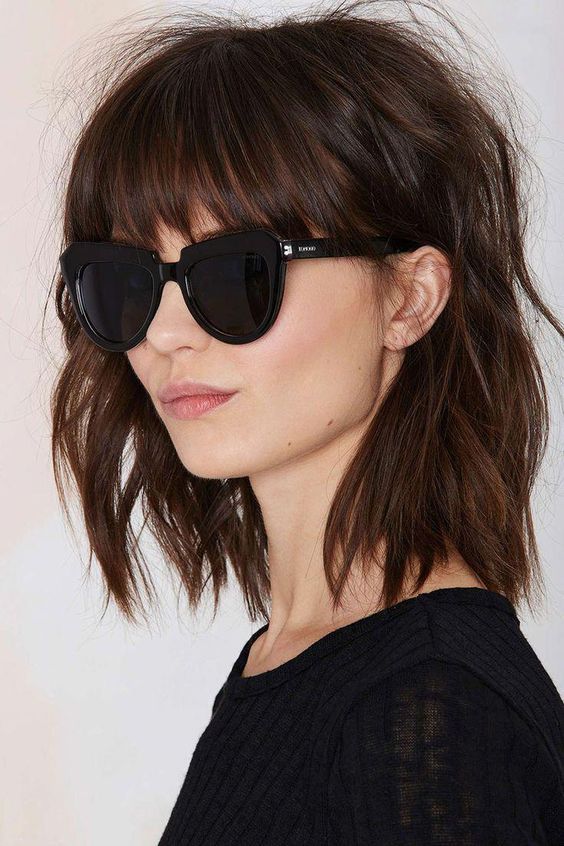 Shaggy brown shoulder-length bob with classic bangs and messy waves, a very rock-n-roll idea to rock