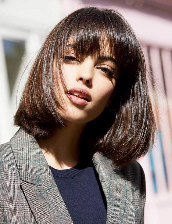 Shiny dark brown long bob with a classic fringe, with a lot of volume and curved ends, an elegant and timeless solution