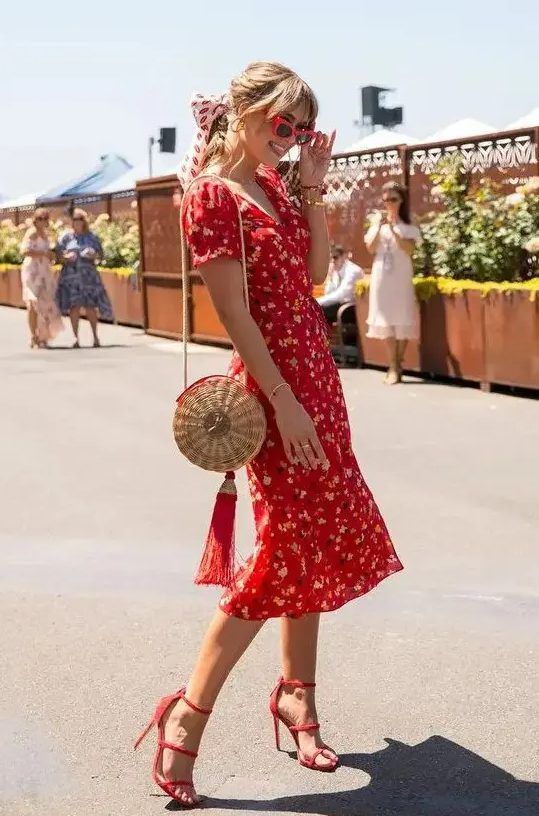 Vintage-styled red floral midi dress with short sleeves and a V-neckline, paired with red heels and a straw bag